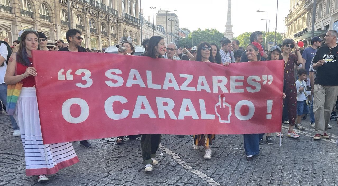 Várias mulheres emancipadas seguram uma grande faixa horizontal onde se pode ler "3 Salazares O Caralho"