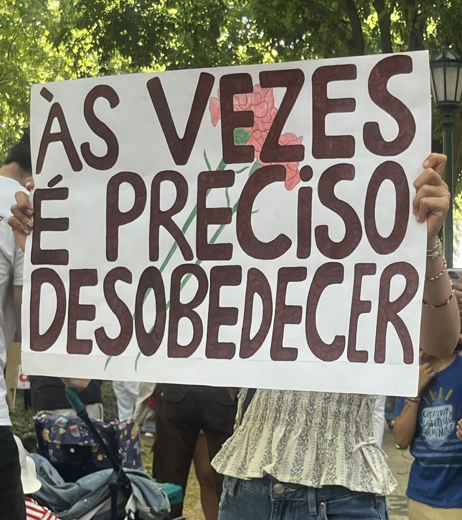 Uma rapariga adolescente segura um cartaz que diz "Às vezes é preciso desobedecer"