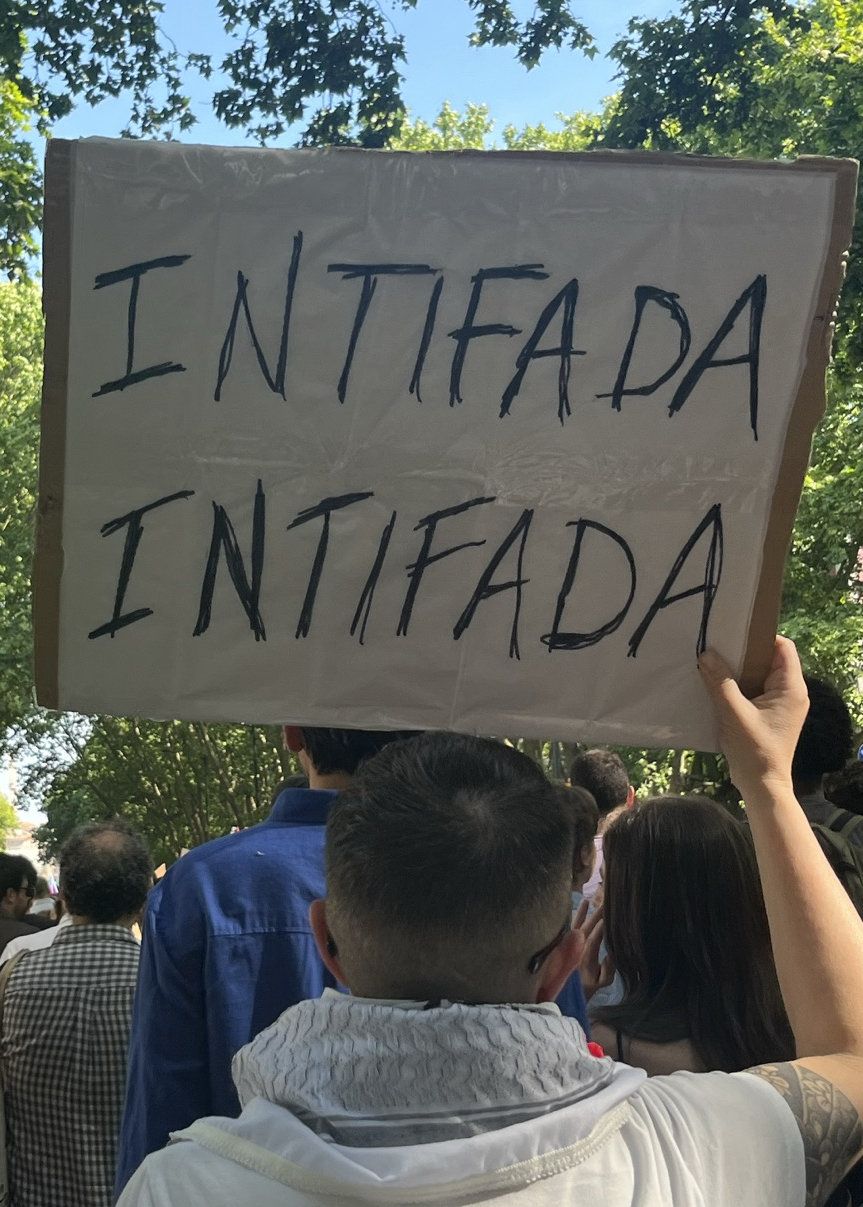 Um senhor de costas segura um cartaz que diz "Intifada Intifada""