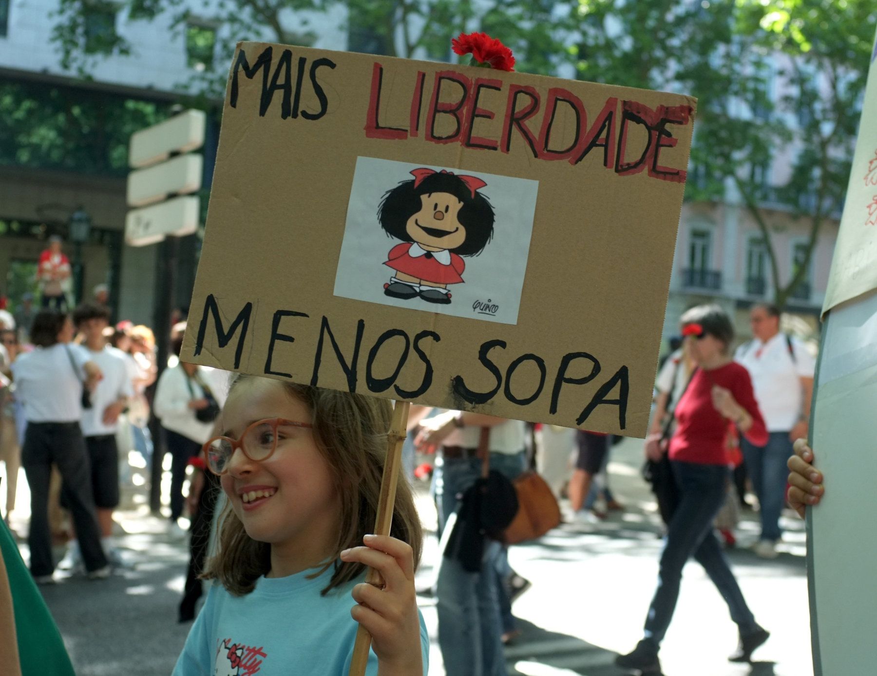 Uma criança segura num cartaz com uma foto da Mafalda do Quino, que diz "Mais Liberdade Menos Sopa"