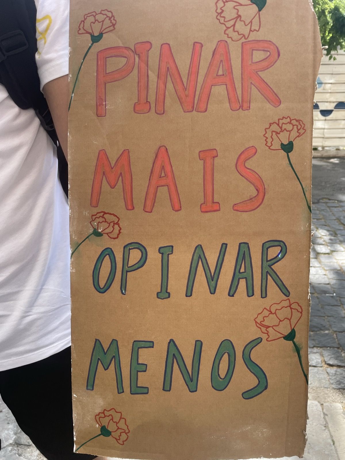 Um cartaz de abril com os dizeres "Pinar mais, opinar menos" e uns cravos desenhados